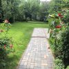 Gepflegter Garten mit Rasenfläche Rosen und Gehweg aus Pflastersteinen